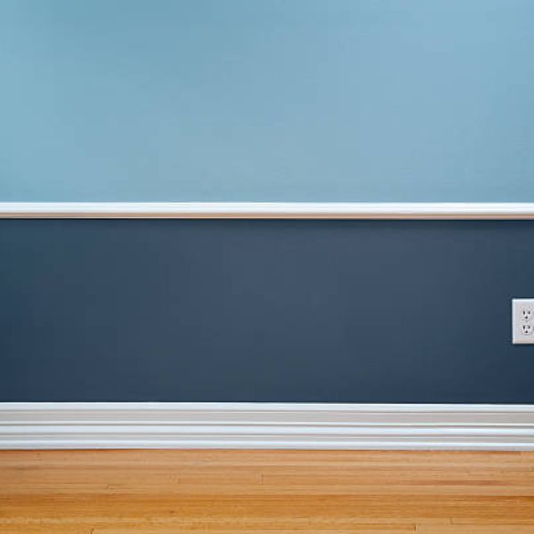 Empty room with wood flooring, blue wainscoting and a power outlet.